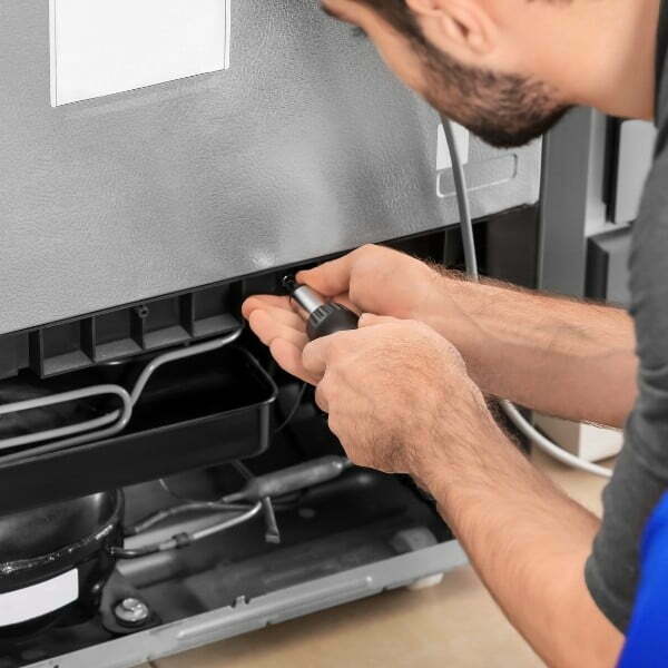 Image depicts a commercial appliance maintenance technician working on a refrigeration unit.