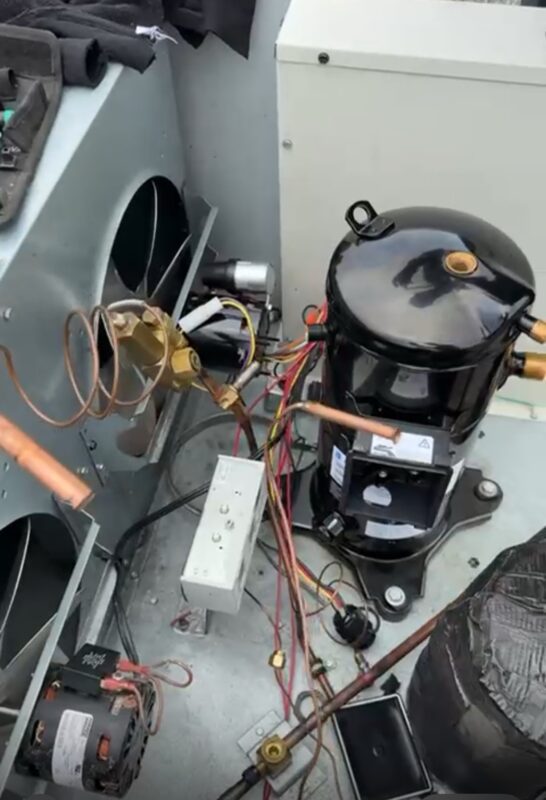 Open commercial refrigeration unit showing compressor, tubing and electrical components