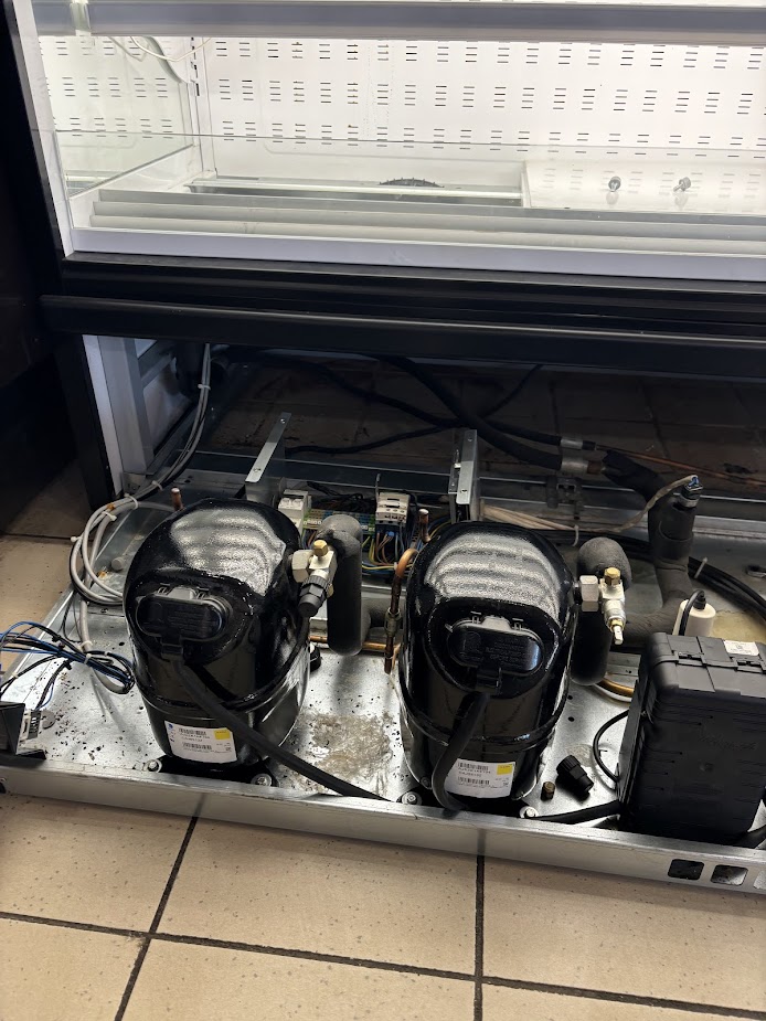 Twin compressors in a commercial refrigerated display case