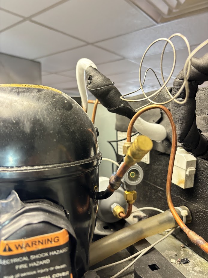 Close-up of commercial refrigeration compressor piping and controls
