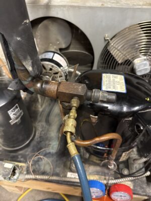 Commercial refrigeration service valve connected to a refrigerant service hose
