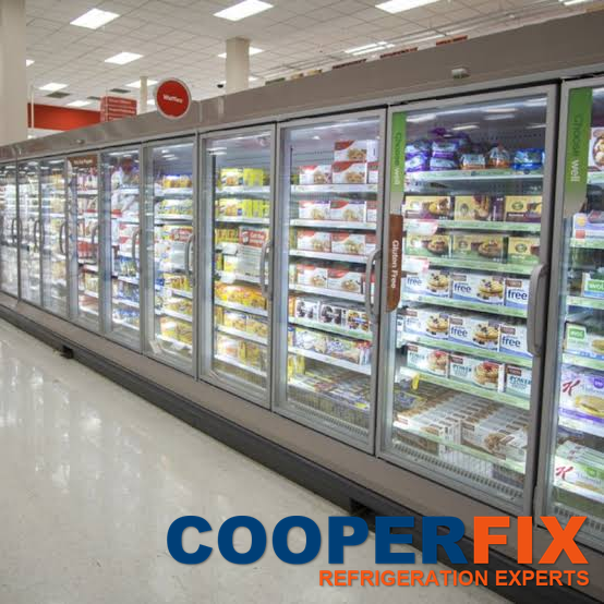 Long row of full-height glass-door freezer displays stocked with frozen food in a supermarket.
