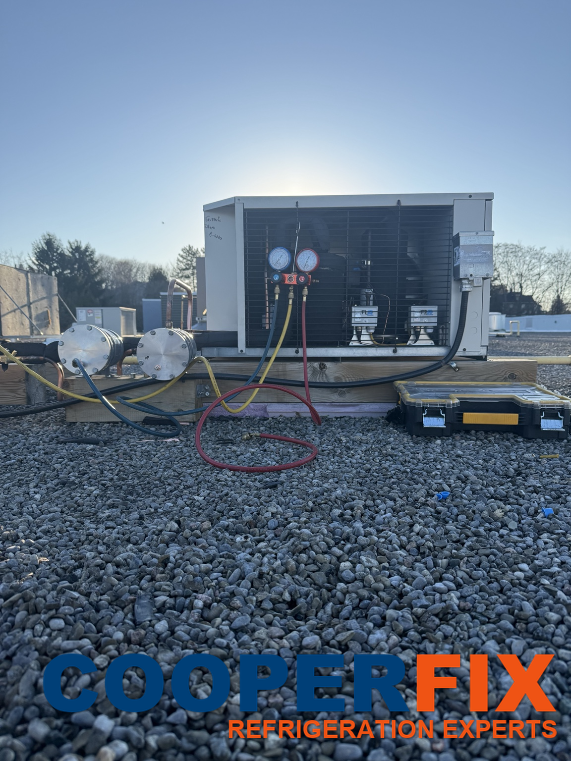 Front view of rooftop refrigeration condensing equipment with connected service gauges.