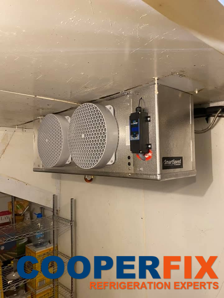 Twin-fan cold-room evaporator assembly with connected refrigerant piping.