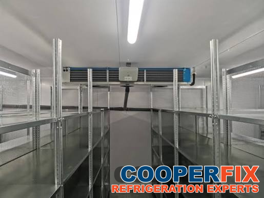 Walk-in cold-room interior with shelving and a ceiling evaporator.