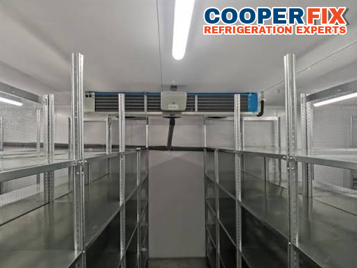 Walk-in cold-room interior with shelving and a ceiling evaporator.