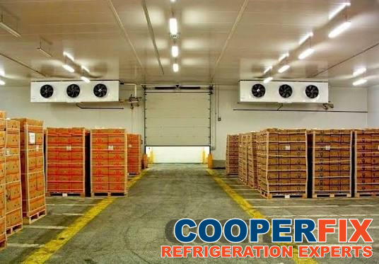 Refrigerated storage room with palletized boxes and two multi-fan evaporator assemblies.