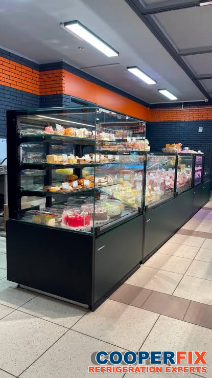 Glass commercial pastry display cases stocked with cakes and desserts.