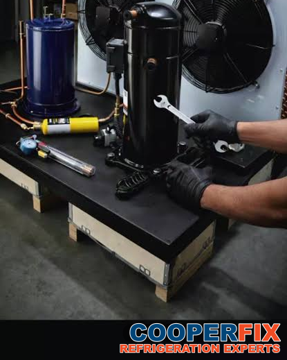 Technician servicing a commercial refrigeration compressor and condensing unit.