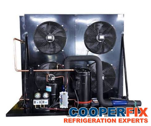 Refrigeration condensing unit with several fans, a compressor and connected piping.